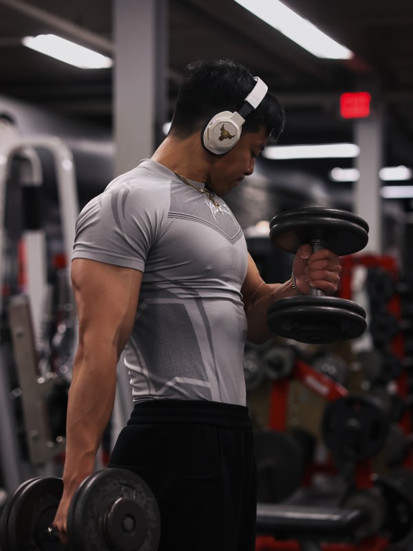 Dumbbell curl under gym lighting, shot from the side