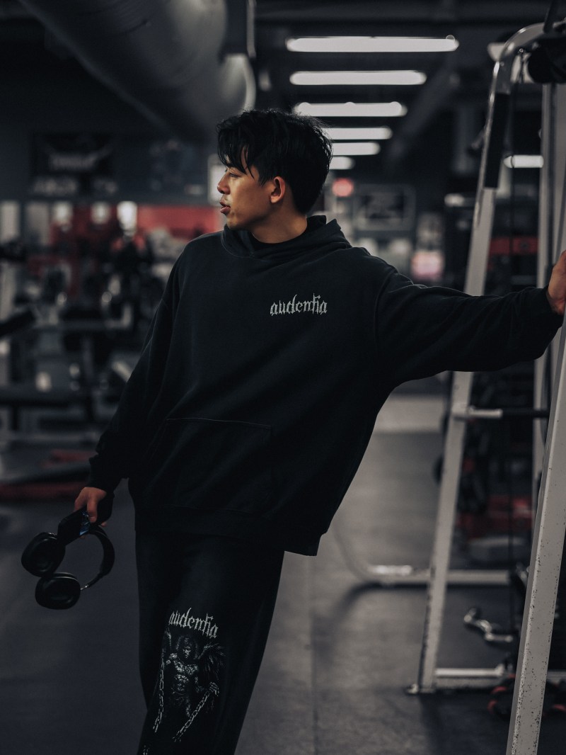 Low-key gym frame in dark training gear, weight in hand
